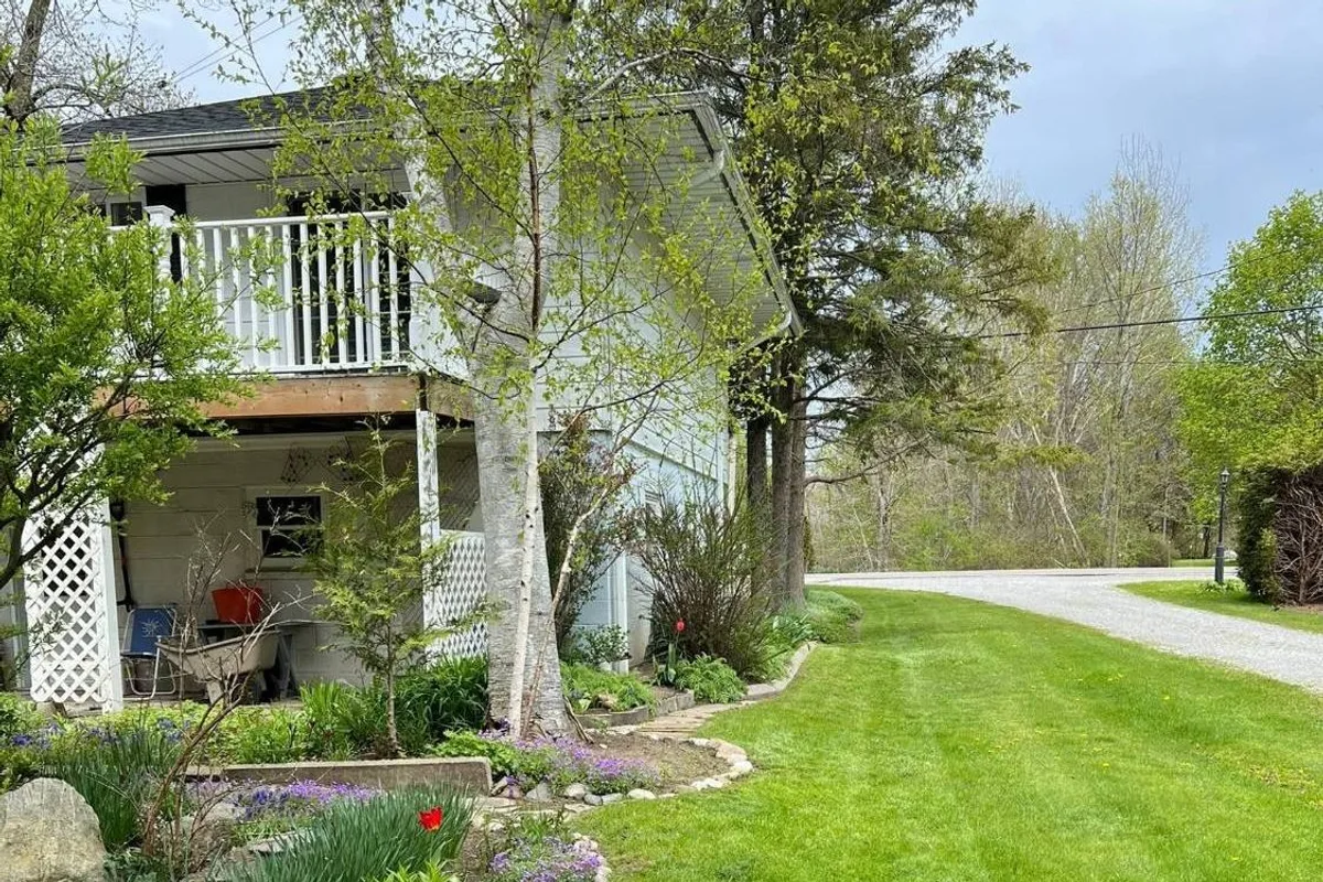 The True Country Property Maintenance team's well-kept lawn and garden beds along a country driveway in Norfolk County